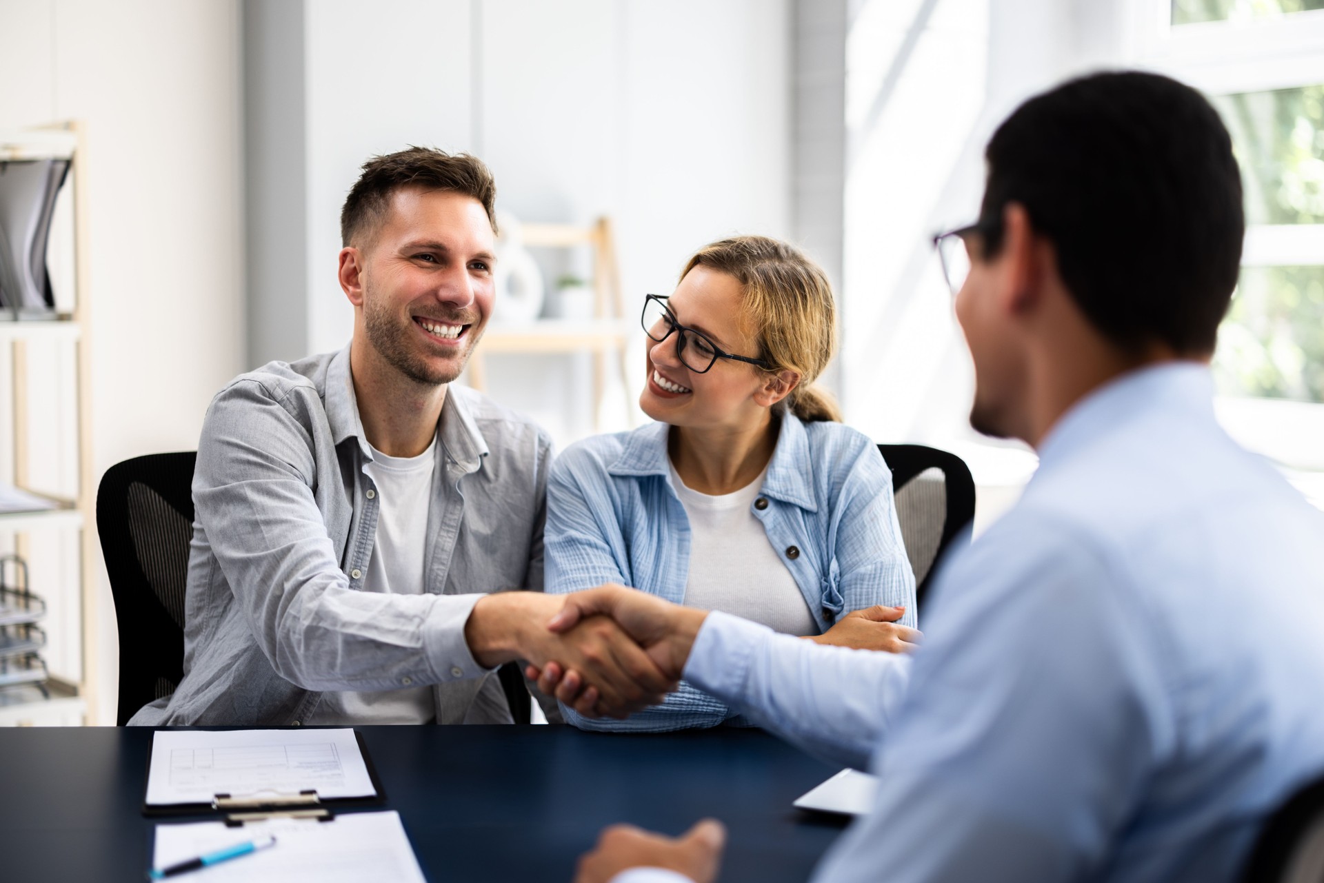 Young couple signing rental contract with real estate agent at apartment viewing